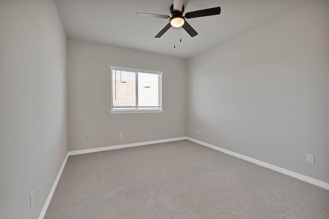 empty room with carpet flooring, a ceiling fan, and baseboards
