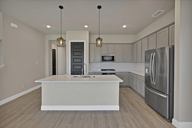 731 Calvin Way, Celina, TX 75009 - kitchen with an island with sink, a sink, gray cabinets, backsplash, and appliances with stainless steel finishes