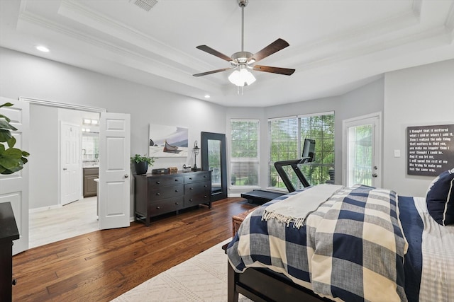 bedroom featuring wood finished floors, recessed lighting, a raised ceiling, and crown molding