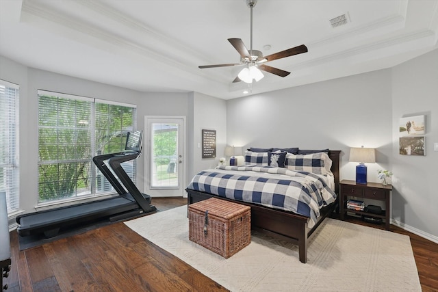 bedroom featuring a raised ceiling, wood finished floors, visible vents, ornamental molding, and access to outside