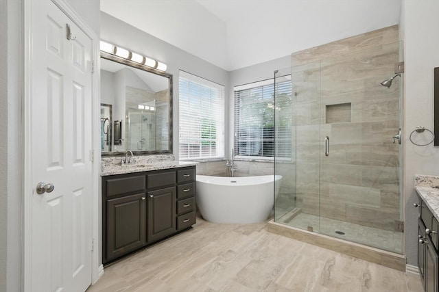 full bath with a freestanding tub, vaulted ceiling, vanity, and a stall shower