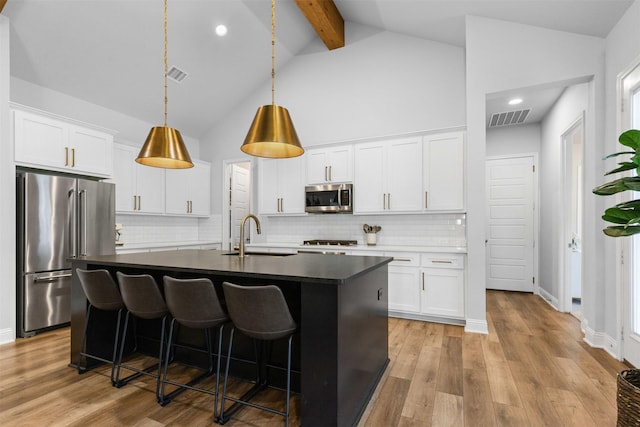 13645 Sweetwalk Pl, Fort Worth, TX 76008 - kitchen with appliances with stainless steel finishes, a sink, a center island with sink, dark countertops, and beam ceiling