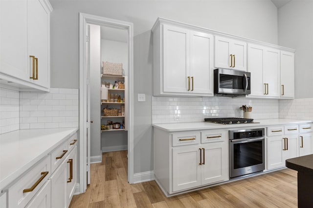 13645 Sweetwalk Pl, Fort Worth, TX 76008 - kitchen featuring appliances with stainless steel finishes, white cabinets, light wood finished floors, and tasteful backsplash