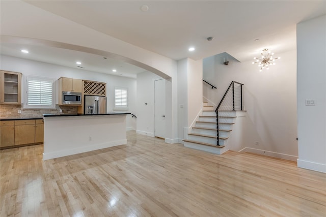 3907 Cole Ave Unit 5, Dallas, TX 75204 - kitchen with dark countertops, glass insert cabinets, light wood-type flooring, arched walkways, and stainless steel appliances