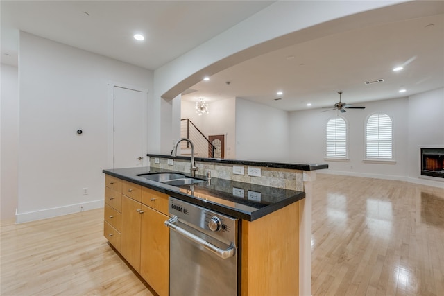3907 Cole Ave Unit 5, Dallas, TX 75204 - kitchen featuring light wood finished floors, arched walkways, a sink, and a lit fireplace