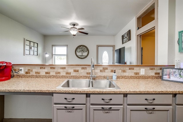 kitchen with a ceiling fan, tasteful backsplash, a sink, and light countertops