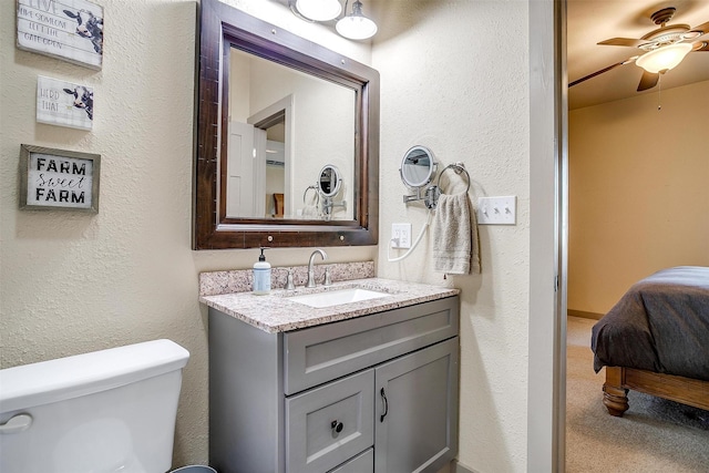 ensuite bathroom with a textured wall, ensuite bath, toilet, and vanity