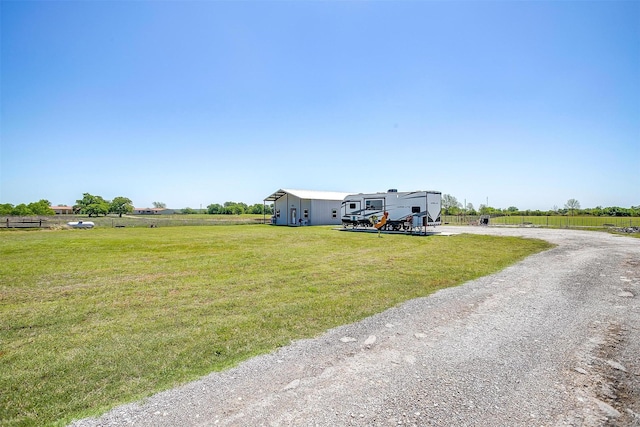 view of front of home featuring driveway, a rural view, and a front lawn