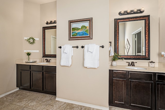 bathroom with two vanities, a sink, and baseboards