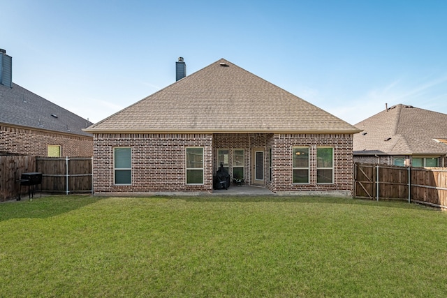 back of property with brick siding, a lawn, a chimney, and a fenced backyard