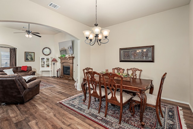 dining space featuring visible vents, dark wood-type flooring, arched walkways, baseboards, and ceiling fan with notable chandelier