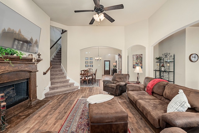 living area with stairway, a ceiling fan, wood finished floors, arched walkways, and a fireplace