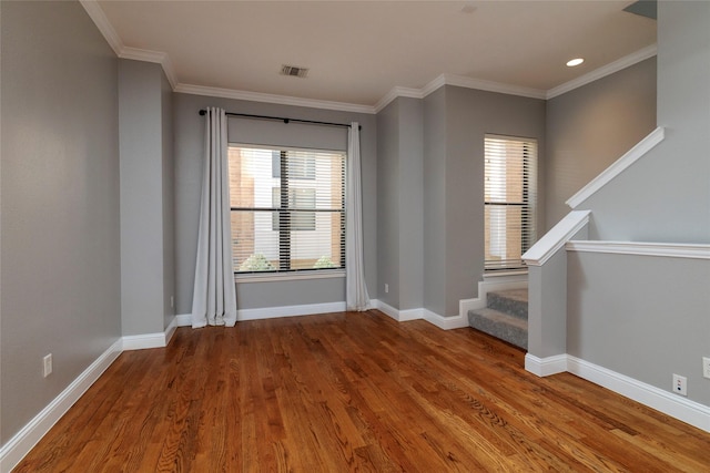 empty room featuring stairway, wood finished floors, visible vents, and plenty of natural light