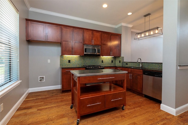 kitchen with dark countertops, a sink, appliances with stainless steel finishes, backsplash, and ornamental molding