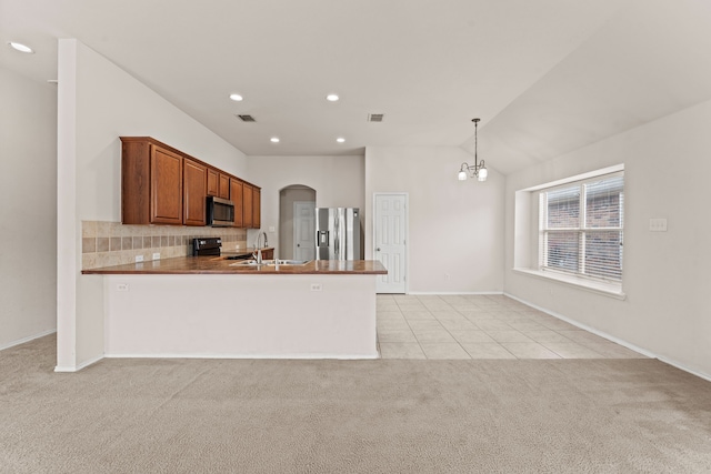 kitchen with a peninsula, light colored carpet, arched walkways, light tile patterned floors, and stainless steel appliances