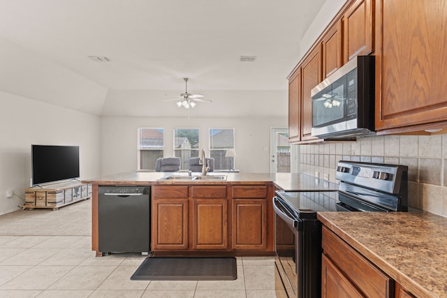 kitchen featuring visible vents, brown cabinetry, a peninsula, a sink, and stainless steel appliances