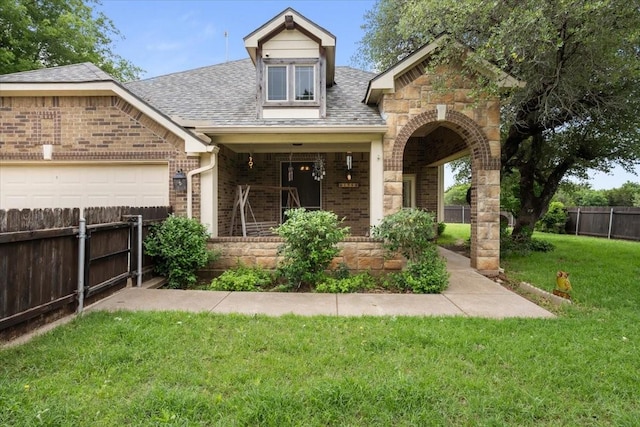 view of front facade featuring fence, a shingled roof, brick siding, a garage, and a front yard