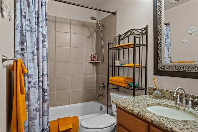 bathroom with vanity, toilet, a textured wall, and shower / tub combo