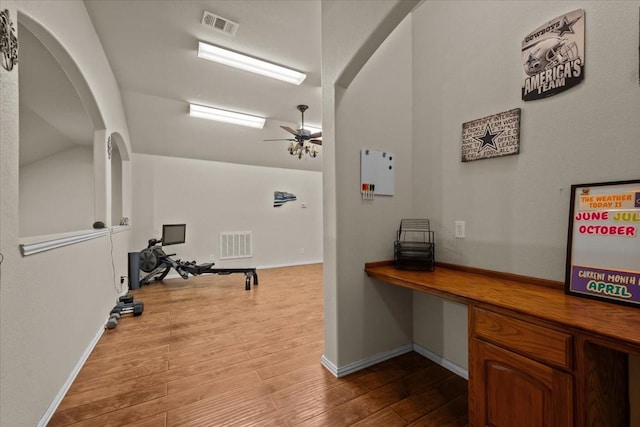home office with arched walkways, baseboards, and dark wood-type flooring