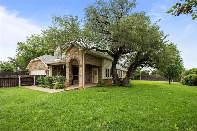 back of house featuring a lawn, brick siding, fence, and stone siding