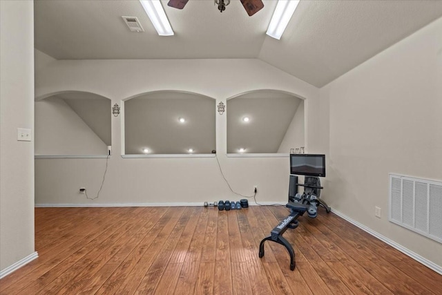 exercise area with a ceiling fan, hardwood / wood-style flooring, visible vents, and vaulted ceiling