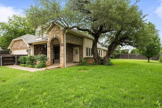 traditional-style home with fence, stone siding, a garage, brick siding, and a front yard