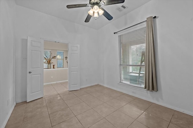 spare room featuring a ceiling fan, visible vents, a healthy amount of sunlight, and light tile patterned floors