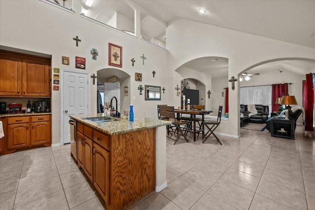 kitchen featuring brown cabinetry, a sink, arched walkways, and light tile patterned flooring