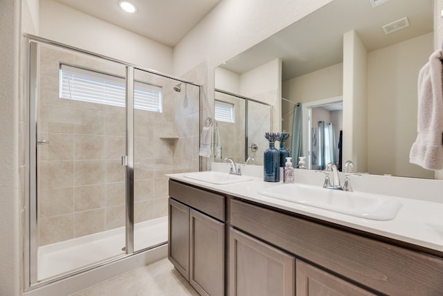 bathroom with visible vents, a sink, double vanity, and a stall shower