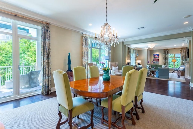 dining room with wood finished floors, visible vents, ornamental molding, and an inviting chandelier