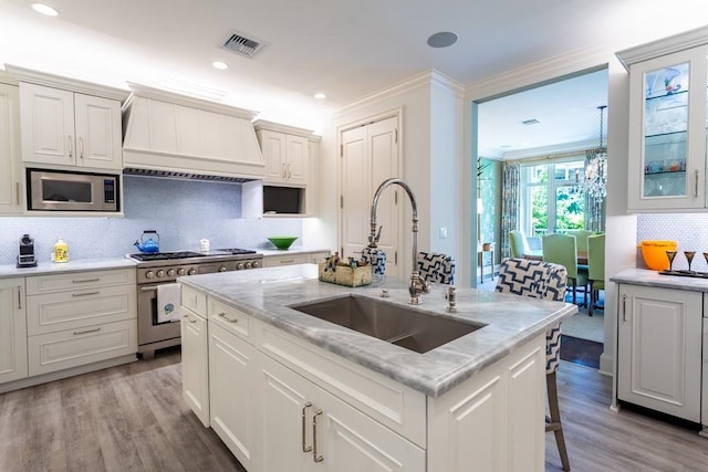 kitchen featuring stainless steel appliances, visible vents, a sink, decorative backsplash, and custom exhaust hood