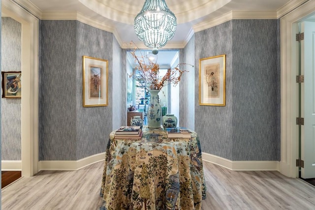 interior space with ornamental molding, an inviting chandelier, wallpapered walls, and wood finished floors