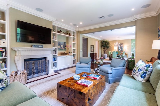 living area with crown molding, built in shelves, an inviting chandelier, a fireplace, and visible vents