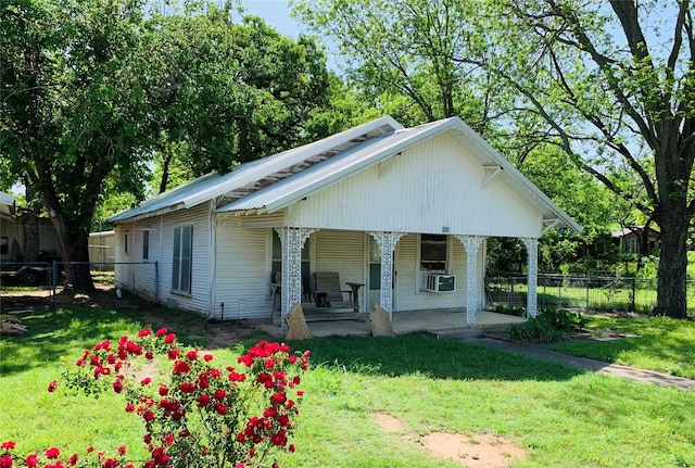 bungalow-style home with a front lawn, fence, a porch, and cooling unit