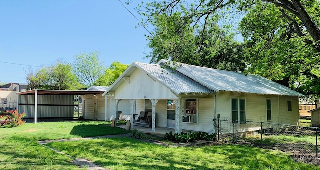 view of front of property featuring fence, cooling unit, a detached carport, a front yard, and metal roof
