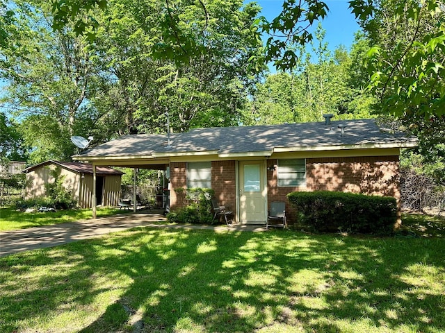 single story home featuring an outdoor structure, driveway, an attached carport, brick siding, and a front yard