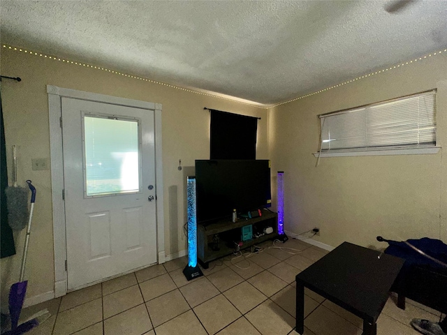 living room with baseboards, a textured ceiling, and light tile patterned floors