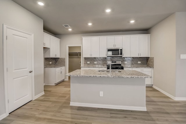 kitchen with visible vents, a sink, light wood-type flooring, decorative backsplash, and appliances with stainless steel finishes