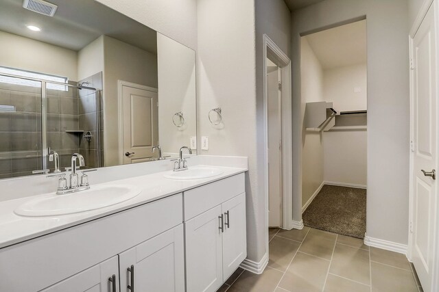 full bath featuring double vanity, a sink, visible vents, and a stall shower