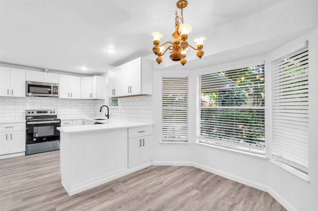 kitchen with backsplash, light countertops, stainless steel appliances, and an inviting chandelier