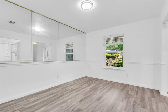 unfurnished room featuring baseboards, wood finished floors, and visible vents