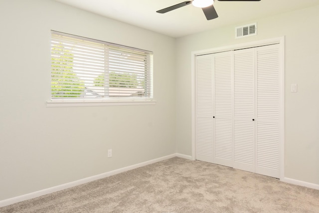 unfurnished bedroom with visible vents, a closet, baseboards, light carpet, and a ceiling fan