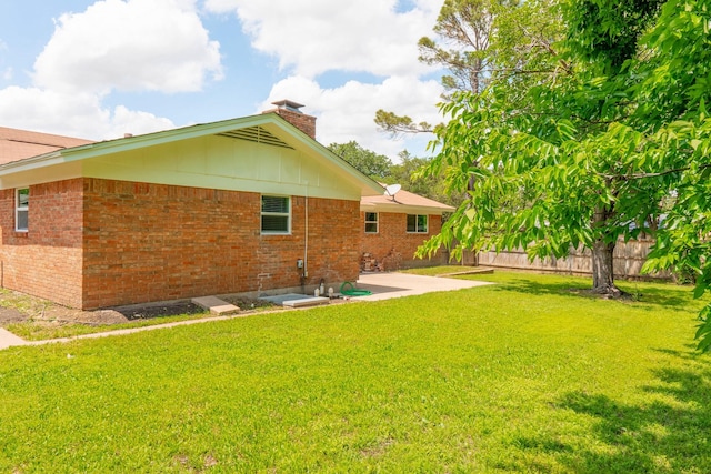 rear view of house with a chimney, fence, a patio, and a yard