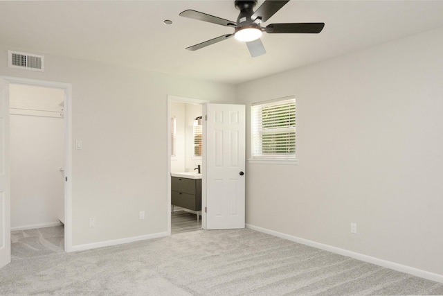 unfurnished bedroom with visible vents, baseboards, light colored carpet, and a spacious closet