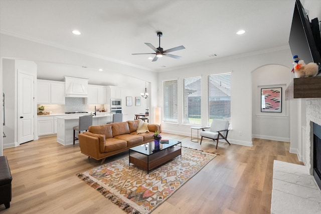 1503 Evening Primrose Dr, Mansfield, TX 76063 - living room featuring a fireplace with flush hearth, a ceiling fan, ornamental molding, light wood-style floors, and recessed lighting