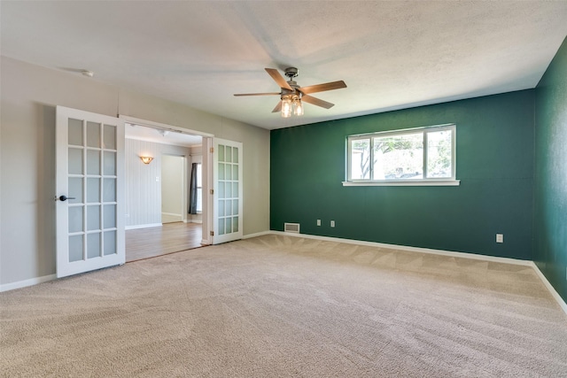 unfurnished room with ceiling fan, french doors, visible vents, and carpet