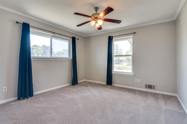 unfurnished room featuring carpet floors, visible vents, a wealth of natural light, and ornamental molding