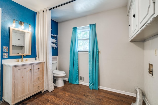 bathroom featuring toilet, baseboards, visible vents, wood finished floors, and vanity