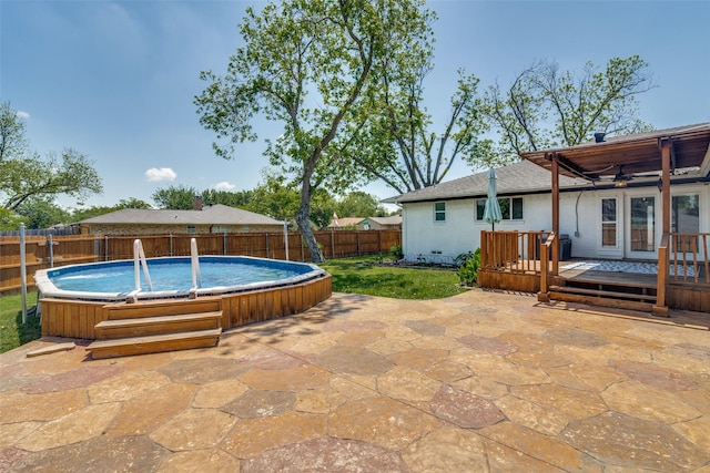 view of swimming pool featuring a fenced backyard, a wooden deck, a ceiling fan, a patio, and a jacuzzi