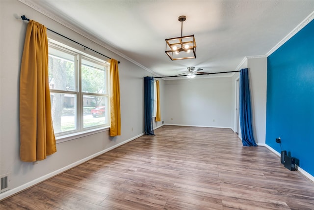 unfurnished dining area with visible vents, baseboards, ceiling fan with notable chandelier, wood finished floors, and crown molding